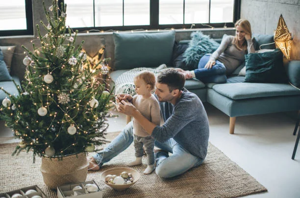 Family decorating a small Christmas tree, enjoying preparing for the holidays